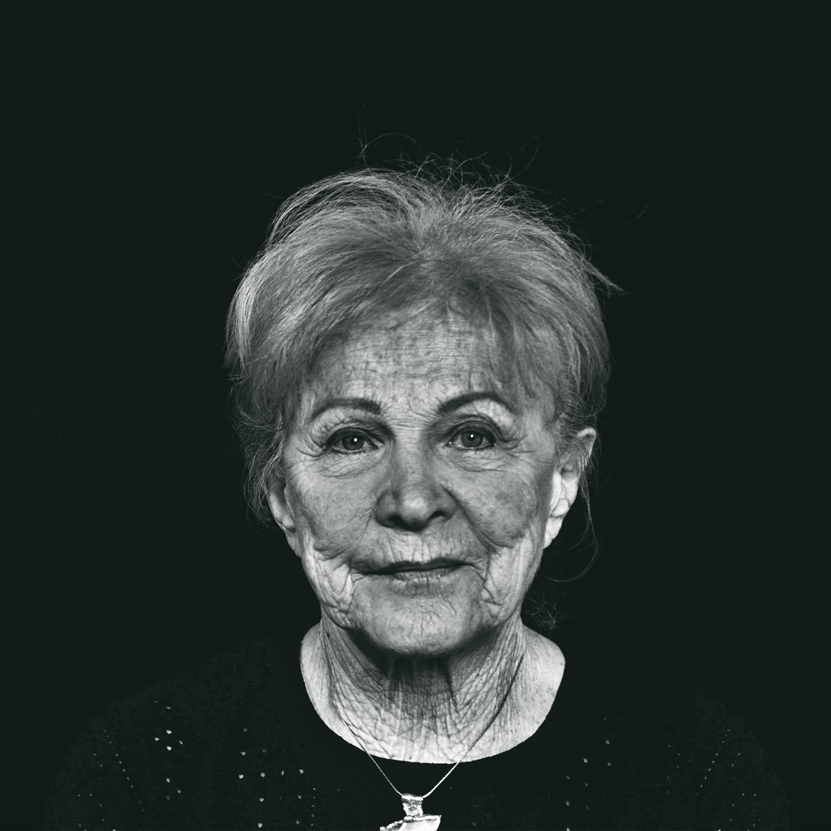 Black and white photo of Marion, plainly dressed in a black shirt, wearing a necklace.